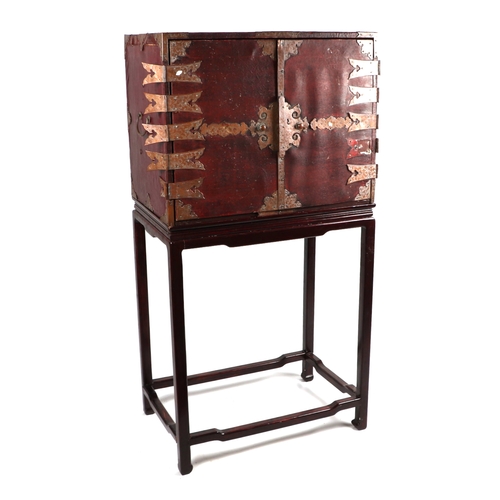 631 - A Chinese leather covered trunk with copper reinforced strap work, the twin doors opening to reveal ... 