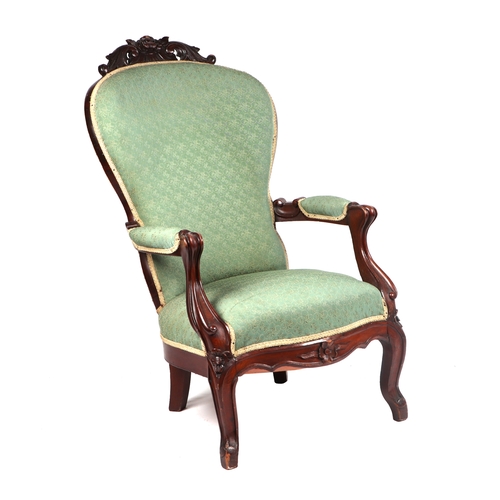 2024 - A Victorian mahogany upholstered armchair with carved back rail, scroll arms and turned front legs.