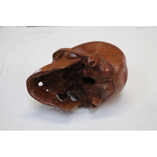 1044 - A memento mori life size carved wooden skull, 20cm long.