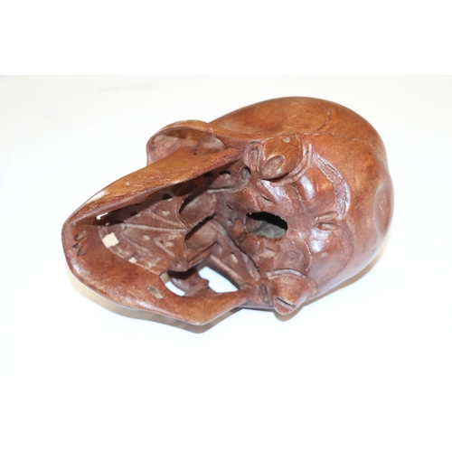 1044 - A memento mori life size carved wooden skull, 20cm long.