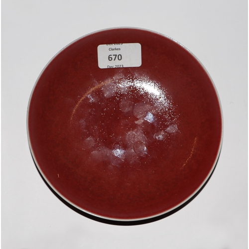 670 - A Chinese red glazed monochrome shallow saucer dish, 17cms diameter.