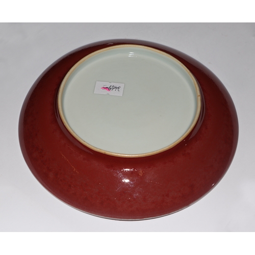 670 - A Chinese red glazed monochrome shallow saucer dish, 17cms diameter.