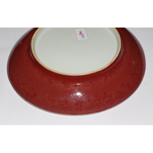 670 - A Chinese red glazed monochrome shallow saucer dish, 17cms diameter.