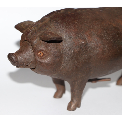 1040 - A cast iron mechanical clockwork table bell in the form of a pig with glass eyes, 14cm long