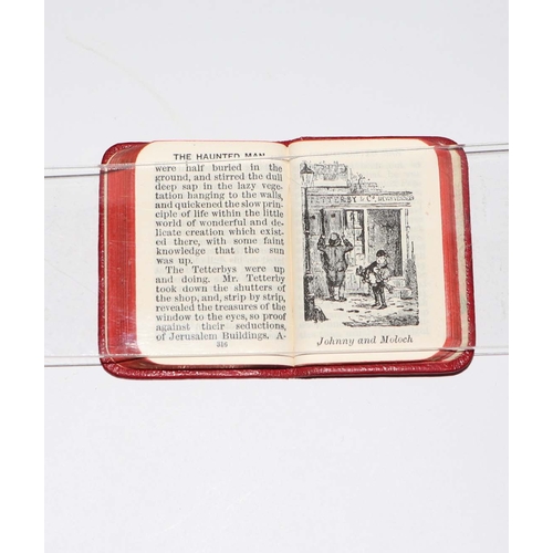 404 - A set of Charles Dickens miniature books on a silver and oak stand, 6.5cms wide.