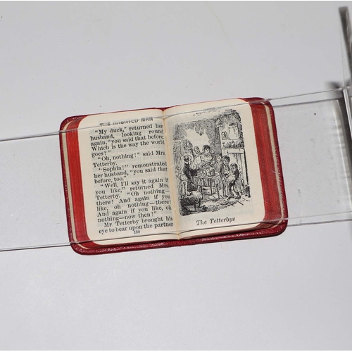 404 - A set of Charles Dickens miniature books on a silver and oak stand, 6.5cms wide.