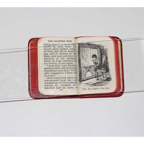 404 - A set of Charles Dickens miniature books on a silver and oak stand, 6.5cms wide.