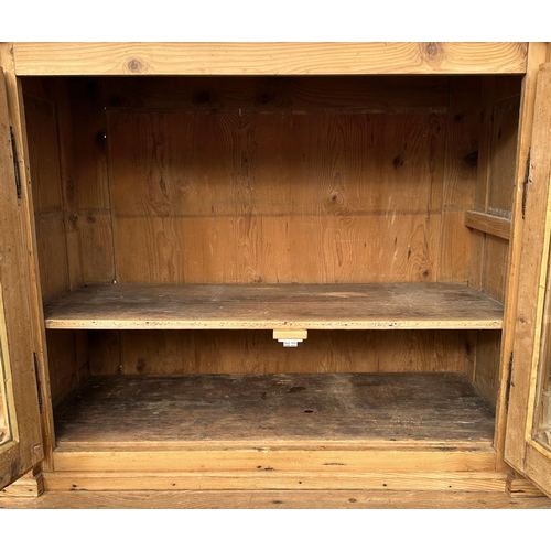 1034 - A stripped pine dresser, the glazed superstructure enclosing a shelved interior above two short draw... 