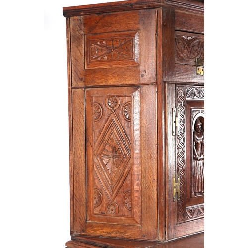 1035 - A 19th century carved oak cupboard, the superstructure with canted corners, the fall-flap frieze cup... 