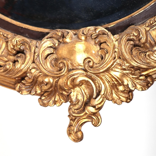 1036 - A large oval giltwood and gesso wall mirror, overall 106 by 153cms.