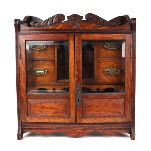 1074 - A late 19th century oak table top smoker's cabinet, the pair of glazed doors enclosing a fitted inte... 