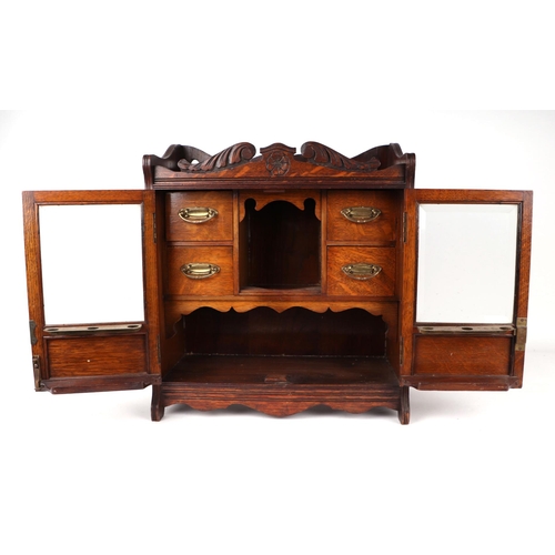 1074 - A late 19th century oak table top smoker's cabinet, the pair of glazed doors enclosing a fitted inte... 