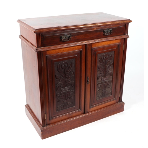 1077 - A late 19th century walnut side cabinet with single frieze drawer above a cupboard with carved panel... 