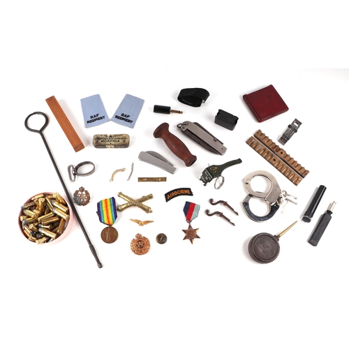 129 - A quantity of assorted militaria to include a bullet mould, a gun oiler, medal group, cap badges, an... 