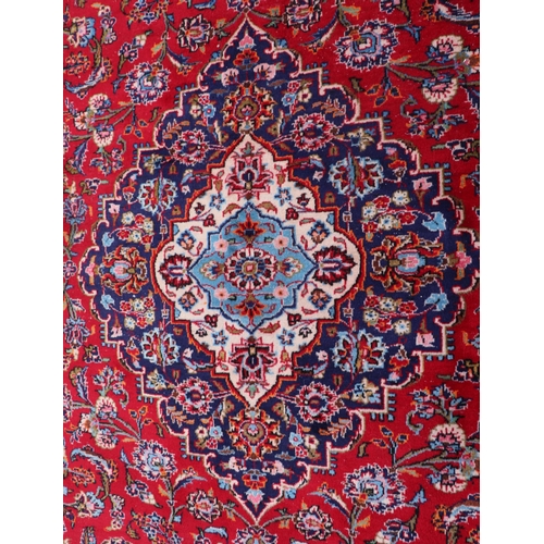 156 - A large Persian Meshed hand knotted wool carpet, the central medallion within a red and floral groun... 