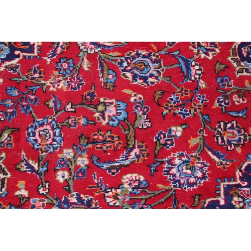 156 - A large Persian Meshed hand knotted wool carpet, the central medallion within a red and floral groun... 