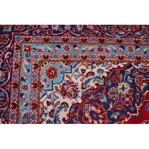 156 - A large Persian Meshed hand knotted wool carpet, the central medallion within a red and floral groun... 