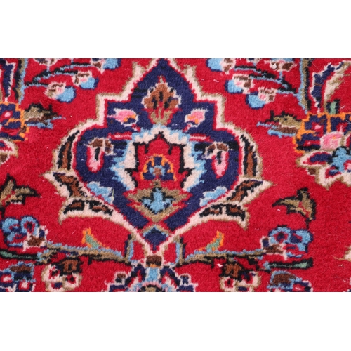 156 - A large Persian Meshed hand knotted wool carpet, the central medallion within a red and floral groun... 