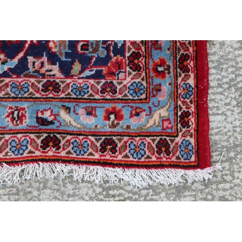 156 - A large Persian Meshed hand knotted wool carpet, the central medallion within a red and floral groun... 