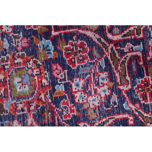 156 - A large Persian Meshed hand knotted wool carpet, the central medallion within a red and floral groun... 