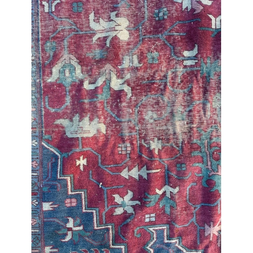 158 - A large Persian carpet, the central blue medallion on a red ground within a repeating floral pattern... 