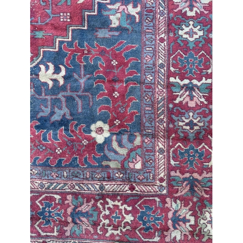 158 - A large Persian carpet, the central blue medallion on a red ground within a repeating floral pattern... 