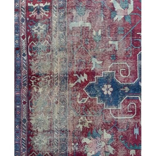 158 - A large Persian carpet, the central blue medallion on a red ground within a repeating floral pattern... 