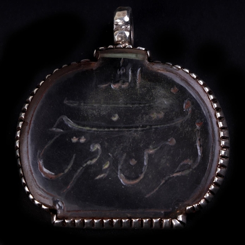 775 - An Islamic white metal mounted rock crystal pendant decorated with Arabic script, 4cms wide.