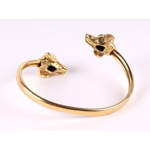 786 - An 18ct gold bangle with dog head terminals and sapphire eyes, 30g.