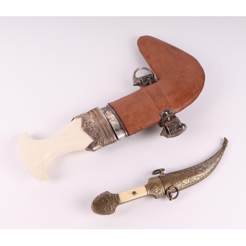 81 - An Arabic Jambiya style dagger with white coloured metal and leather scabbard, 28cms long; together ... 