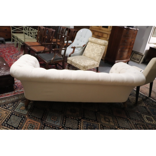 1043 - A Chesterfield cream upholstered three-seater  sofa on turned  front legs, approx 190cms wide.