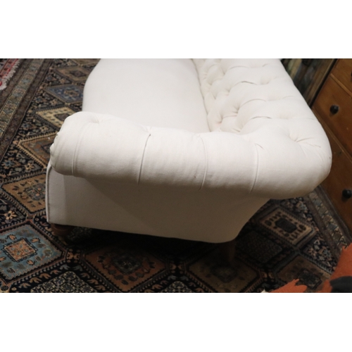 1043 - A Chesterfield cream upholstered three-seater  sofa on turned  front legs, approx 190cms wide.