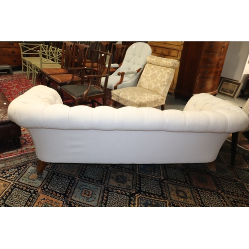 1043 - A Chesterfield cream upholstered three-seater  sofa on turned  front legs, approx 190cms wide.