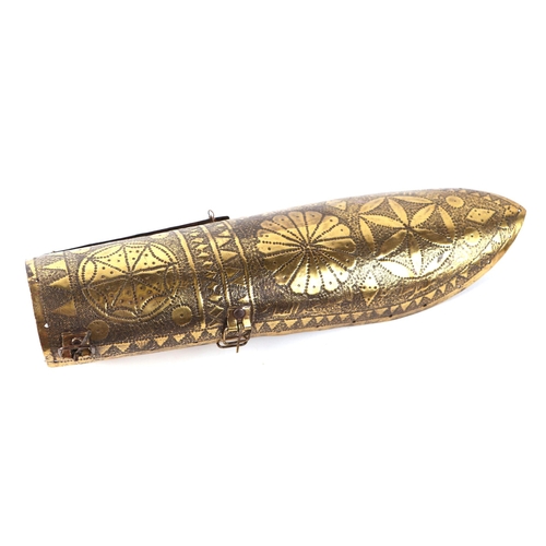 115 - A North Indian brass arm guard decorated with roundels and script, 34cms long.