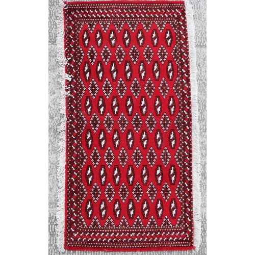 140 - A small Persian Turkoman rug with repeat stylised design on a red ground, approx 130 by 60cms.