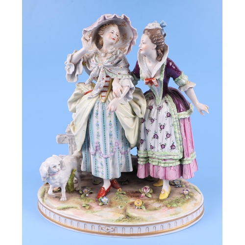 286 - A continental porcelain group depicting two ladies standing by a gate with a spaniel dog, 26cms high... 