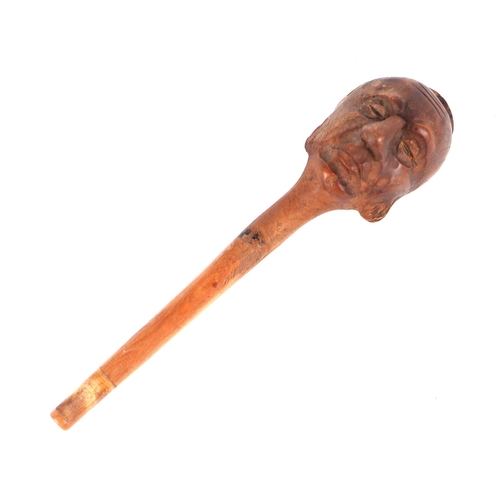 360 - A folk art treen tobacco pipe, the bowl carved in the form of a mans head, 14cms long.