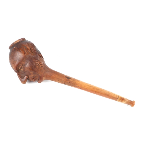 360 - A folk art treen tobacco pipe, the bowl carved in the form of a mans head, 14cms long.