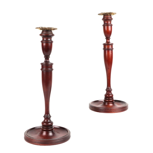 384 - A pair of carved mahogany candlesticks with brass sconces, 32cms high (2).