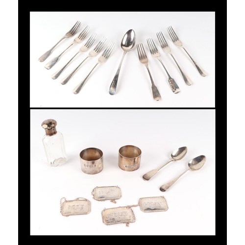 550 - A pair of silver napkin rings; four silver bottle labels; a silver topped scent bottle and a quantit... 