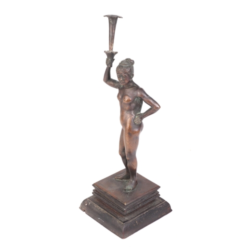 634 - An early 20th century Burmese bronze figure depicting a naked female holding  a torch on an ebonised... 