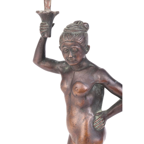 634 - An early 20th century Burmese bronze figure depicting a naked female holding  a torch on an ebonised... 