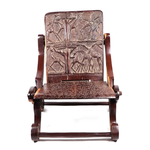 751 - An African hardwood folding chair with a carved panel seat and back.