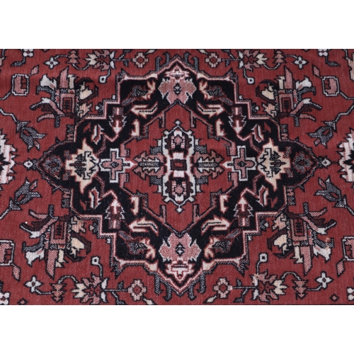 134 - A small Persian rug with central medallion within a multi border, on a dark pink ground, 93 by 134cm... 