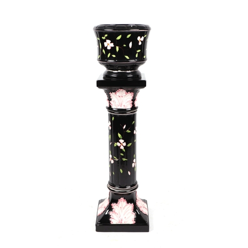 306 - A ceramic jardiniere on stand decorated with flowers on a black ground, 42cms high.