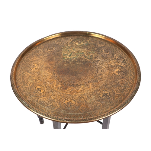 638 - A Middle Eastern brass tray-top table, 59cms diameter.