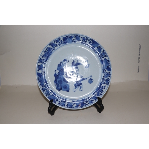 679 - A Chinese blue & white plate decorated with a robed man with four young boys, 22cms diameter.