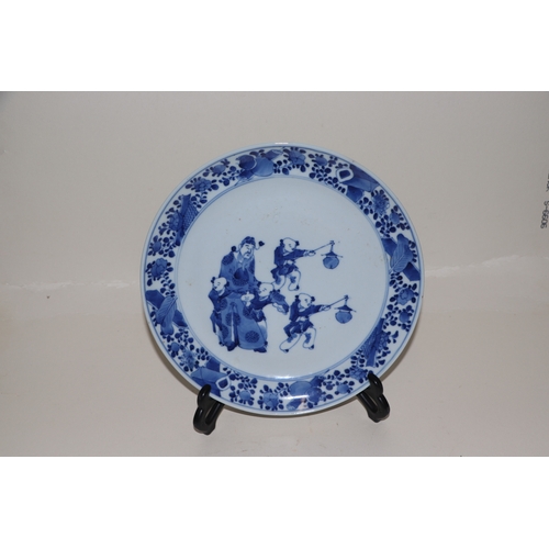 679 - A Chinese blue & white plate decorated with a robed man with four young boys, 22cms diameter.