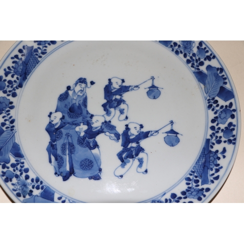 679 - A Chinese blue & white plate decorated with a robed man with four young boys, 22cms diameter.