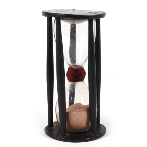 384 - An early 18th / late 19th century hour glass within a treen cage, 18cm high.